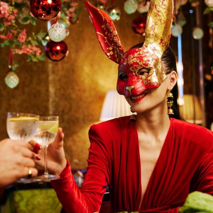 Woman in red dress and rabbit mask holding a cocktail