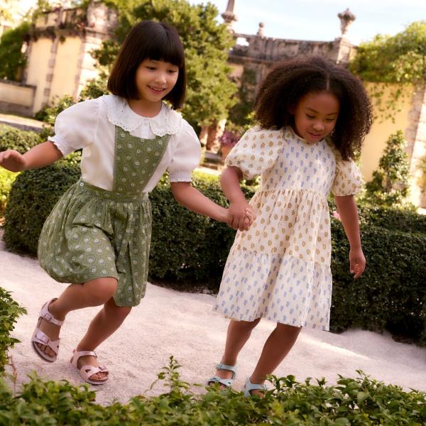 Two children in dresses holding hands 